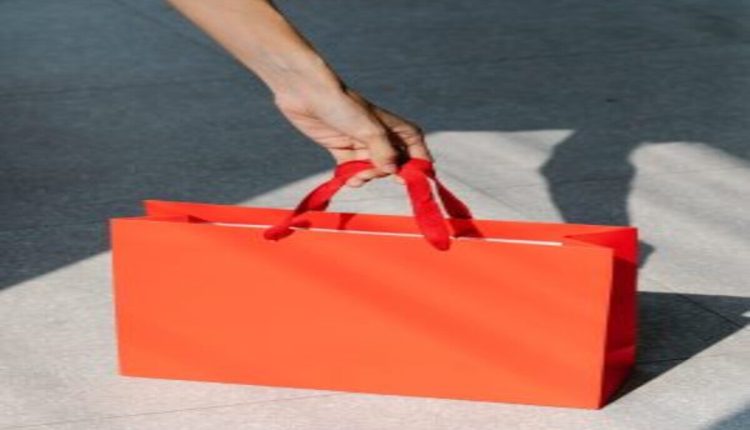 Une main qui porte un sac orange